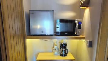 Cocina compacta equipada con refrigerador, microondas, cafetera y una pequeña encimera.