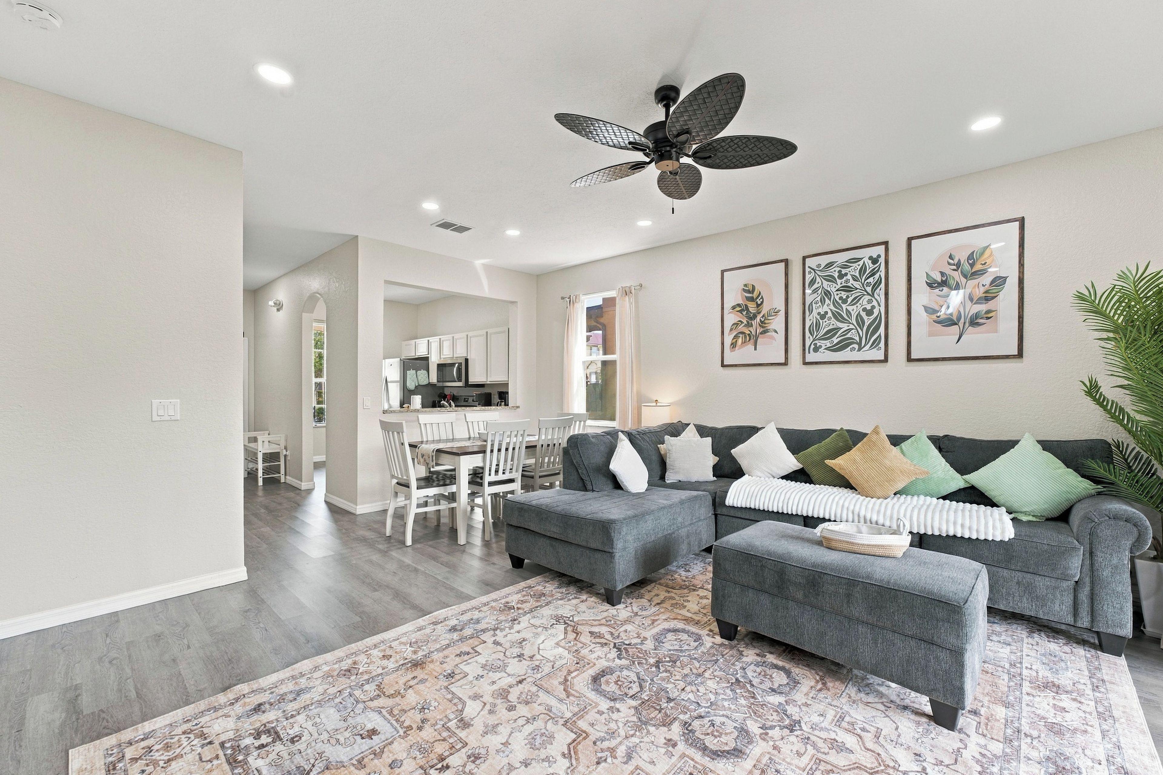 A modern living room with a grey sofa, ottoman, and patterned rug.