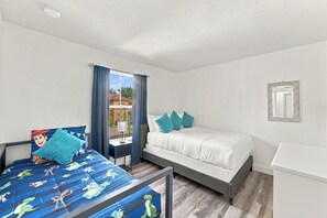 A bedroom with a bed, a bedside table, a lamp, and a window with curtains. - Regal Palms Haven | 4BR/3.5BA Davenport Resort Townhome with Pool (Davenport)