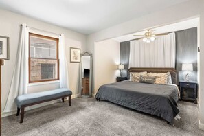 Ein Schlafzimmer mit einem Bett, einer Bank, einem Spiegel und zwei Nachttischen.