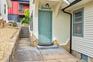 Une maison avec une porte de couleur turquoise, une enseigne indiquant qu’il s’agit d’une laverie au-dessus de la porte, et un petit jardin devant la maison avec des marches menant à l’entrée.
