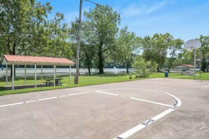 Una cancha de baloncesto al aire libre con una mesa de picnic y un área de estar cubierta.