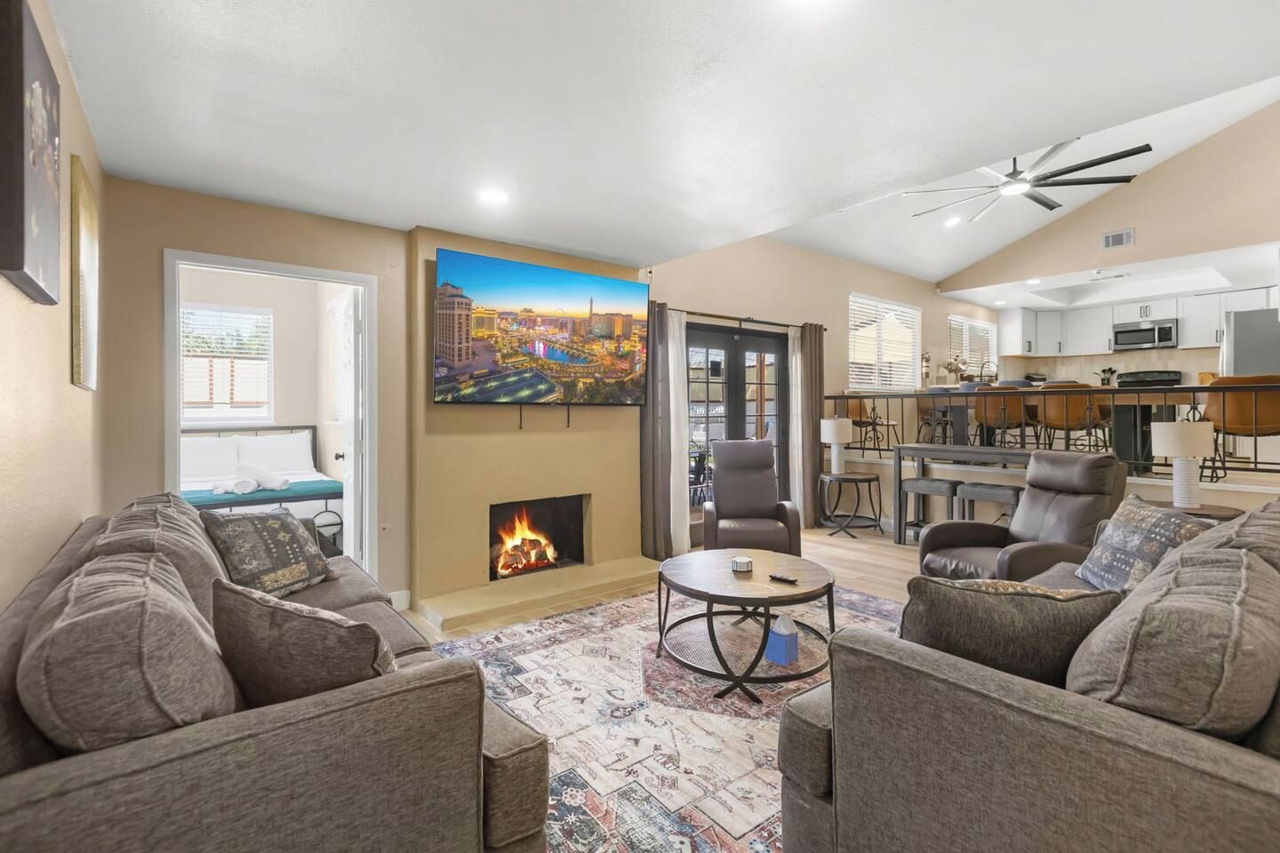 A living room with a fireplace, a dining area, and a kitchen.