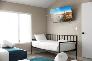 A bedroom with a bed, a window with blinds, a wall-mounted TV, and a door. - Pool & Hot tub • Arcades • Air Hockey • Foosball • Mini-Golf (Las Vegas)