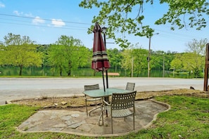 A patio with a table and chairs, an umbrella, and a view of a lake. - The Ravens Roost Lakeview Retreat-Walk to the Park/Fishing/Boating (Rockaway Beach)