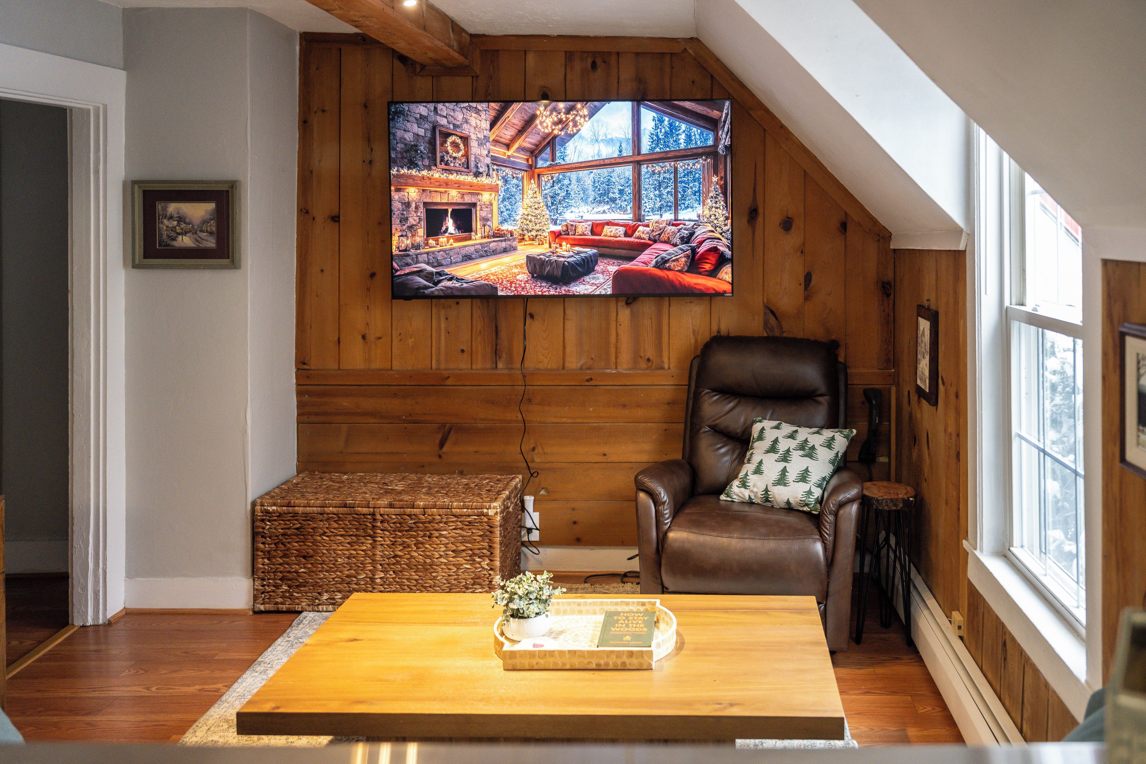 Una sala de estar acogedora con chimenea, un sillón de cuero y un ventanal amplio.