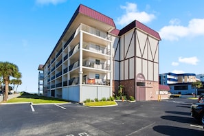 Un hotel de varios pisos con un diseño arquitectónico distintivo, que presenta una combinación de colores blanco y marrón, y un techo rojo.
