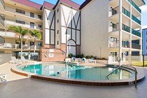 Un hotel con piscina, varios balcones y un diseño arquitectónico moderno.