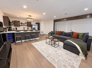A modern kitchen with a central island, bar stools, and a built-in refrigerator. - Heights Gem Chef's Kitchen 5 Min to Downtown (Houston)