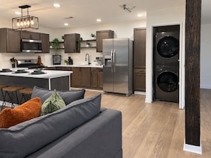 A modern kitchen with a central island, stainless steel appliances, and a built-in washer and dryer. - Heights Gem Chef's Kitchen 5 Min to Downtown (Houston)
