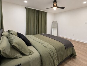 A bedroom with a bed, a ceiling fan, a mirror, and a window with curtains. - Heights Gem Chef's Kitchen 5 Min to Downtown (Houston)