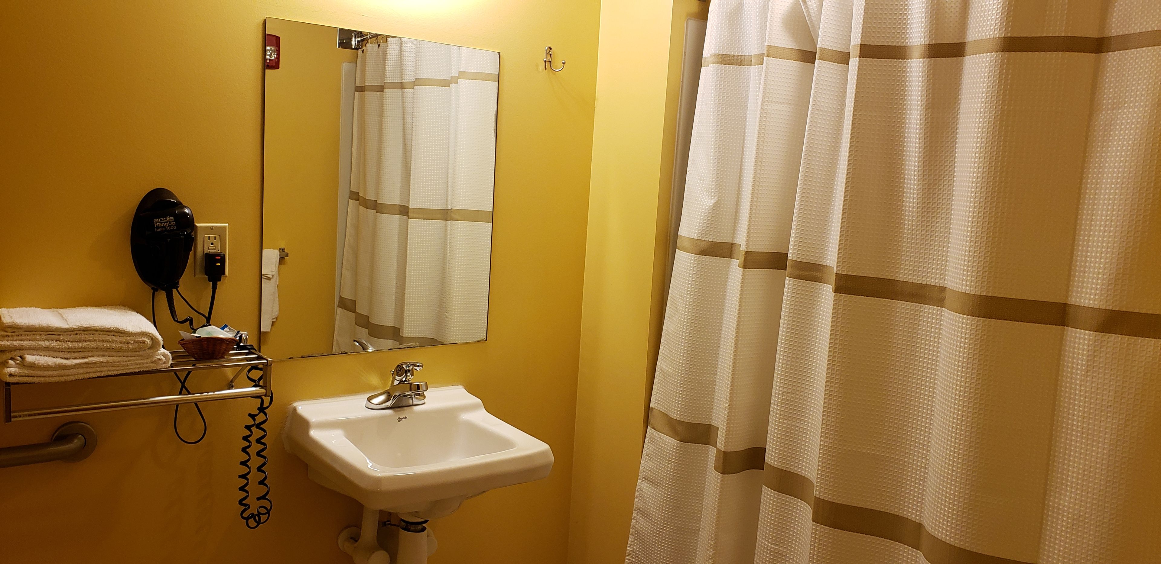 A bathroom with a sink, a hairdryer, and a towel rack.
