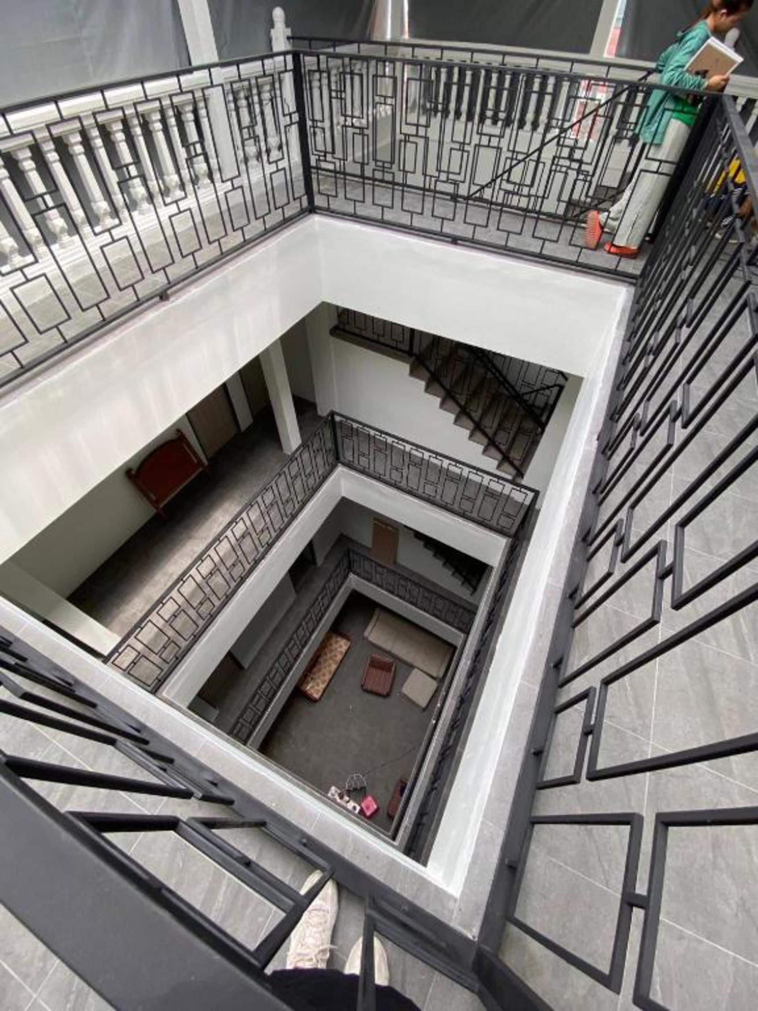 Ein mehrgeschossiges Atrium mit einem zentralen, offenen Bereich, umgeben von Balkonen mit Metallgeländern.