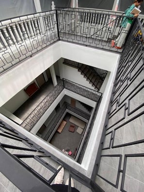 A multi-level atrium with a central open space, surrounded by balconies with metal railings. - Y room Yaowarat (Bangkok)