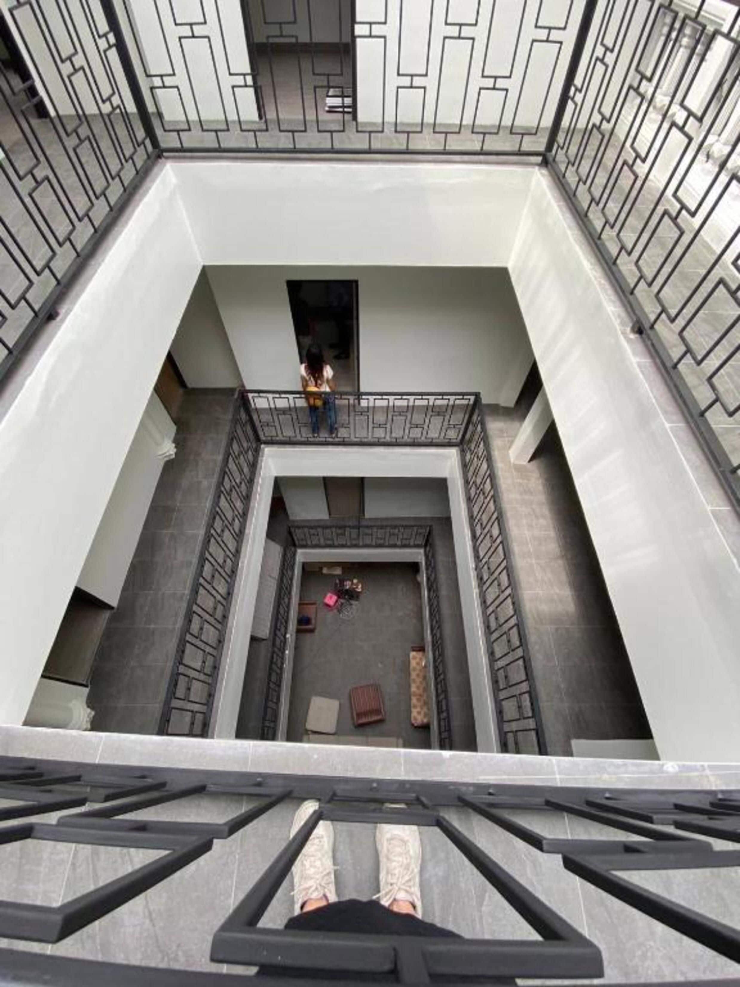 Ein mehrgeschossiges Atrium mit einem zentralen, offenen Bereich, umgeben von Wänden mit geometrischen Mustern.