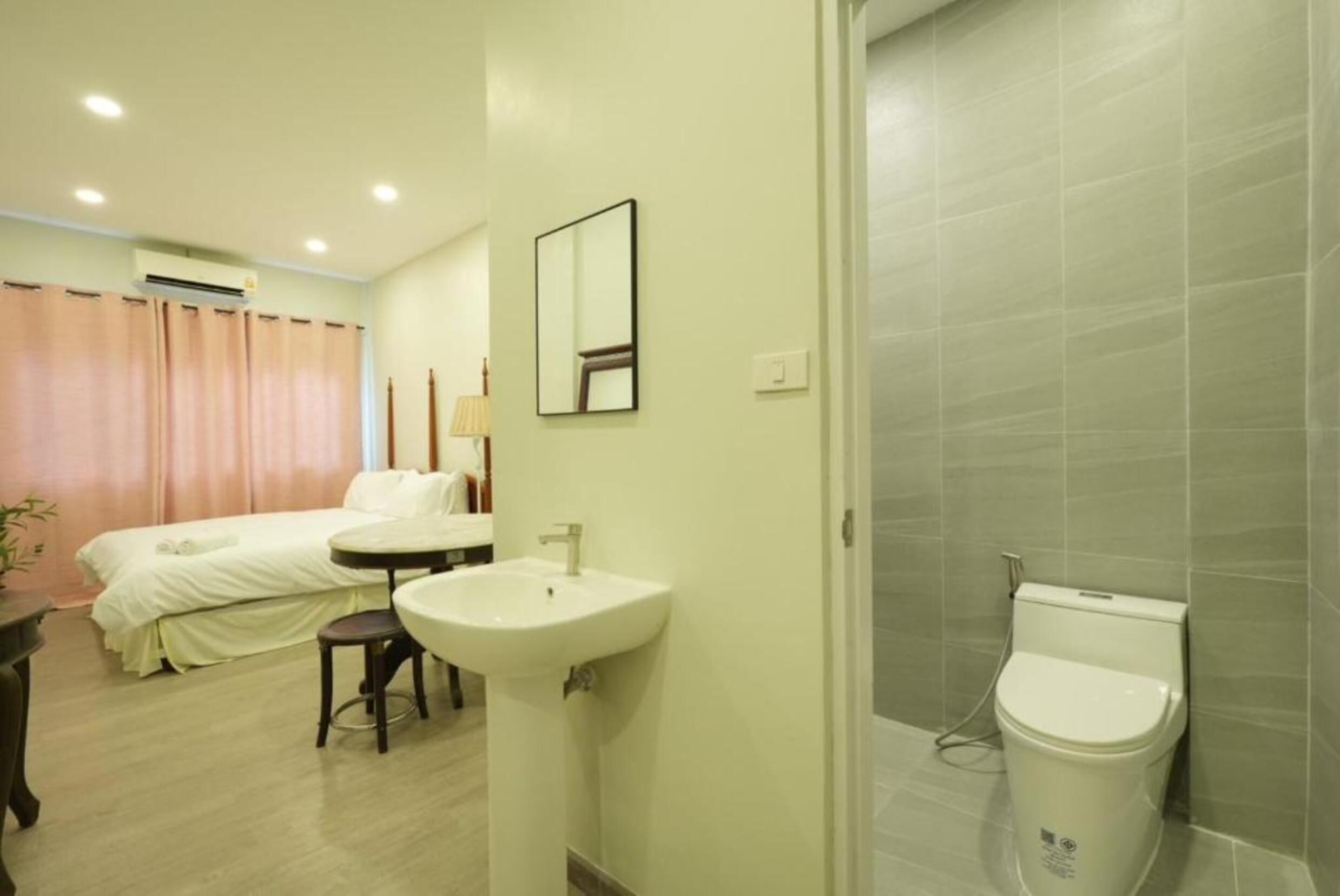 Ein Hotelzimmer mit Bett, Nachttisch, Spiegel, Waschbecken und Toilette.