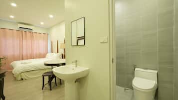 Une chambre d’hôtel comprenant un lit, une table de chevet, un miroir, un lavabo et des toilettes.