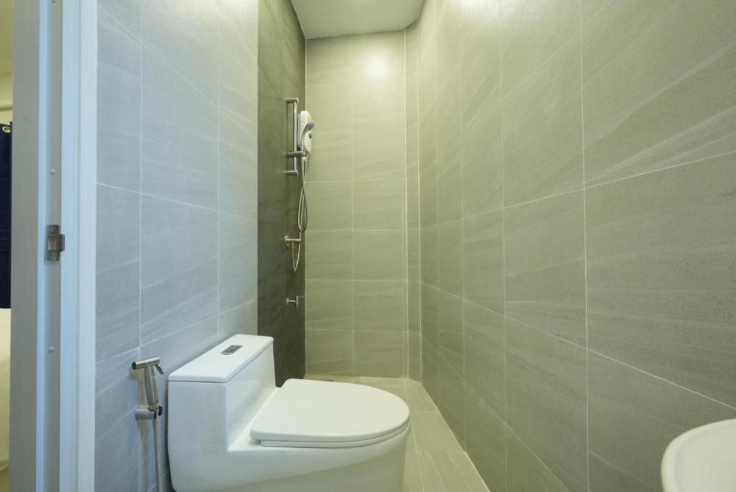 Ein kleines, modernes Badezimmer mit Toilette, Dusche und einem fest montierten Toilettenpapierhalter.