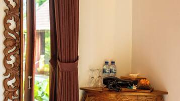 A room with a mirror, a wooden table with bottles, and a curtain.