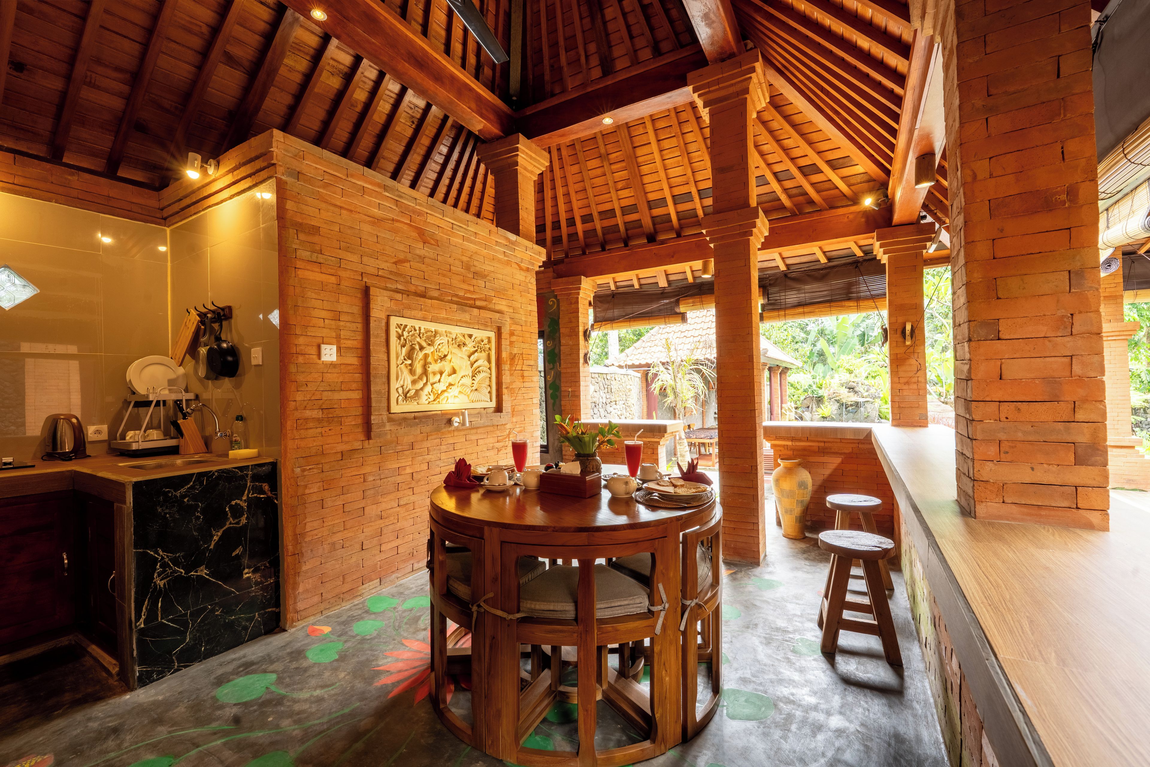 A rustic interior with a wooden dining table, chairs, and a brick wall with a relief sculpture.