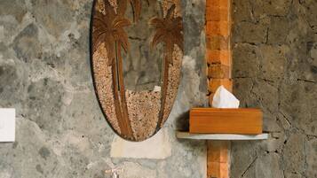 A bathroom with a white sink, a mirror with a palm tree design, and a soap dispenser.