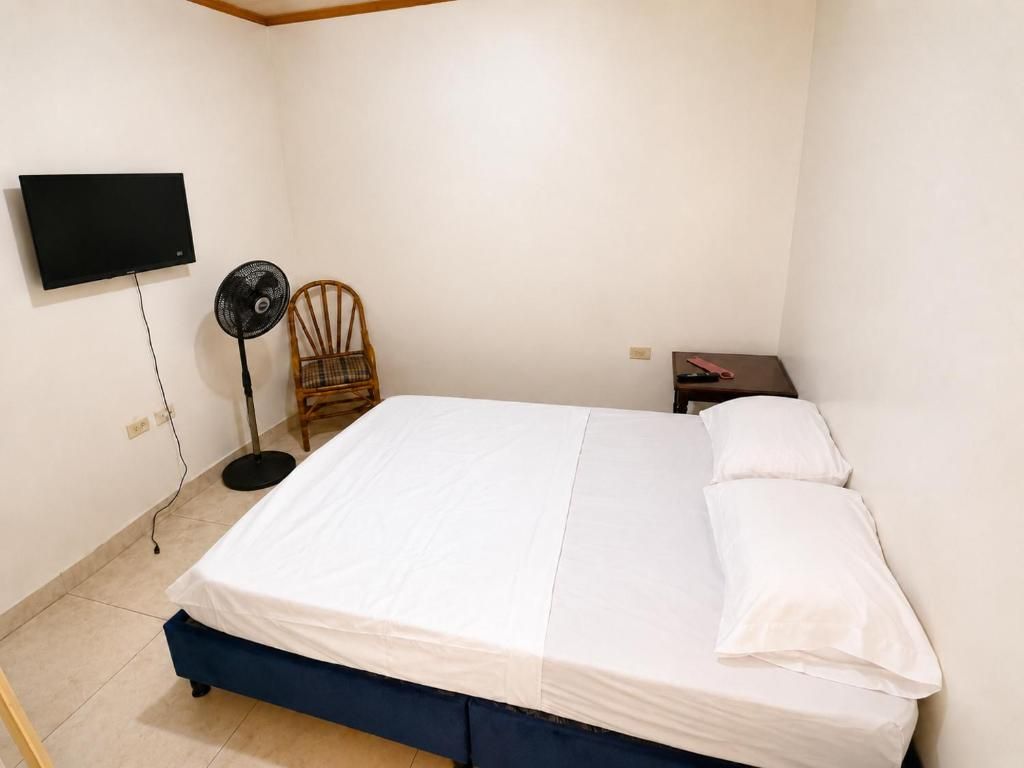 Un dormitorio con cama, una silla, un televisor y una mesita de noche.