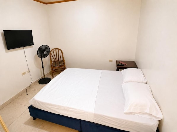 A bedroom with a bed, a chair, a TV, and a bedside table. - Casa Yarumo (Neiva)
