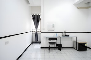 A small, modern kitchenette with a white countertop, a black chair, and a black trash bin. - B room Hualumphong (Bangkok)