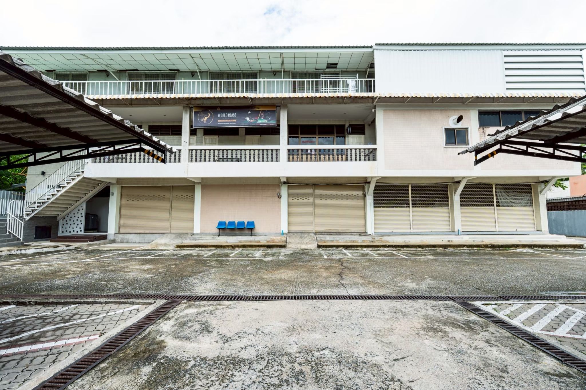 Un edificio de varios pisos con estacionamiento techado, una escalera y un letrero que indica un establecimiento de clase mundial.