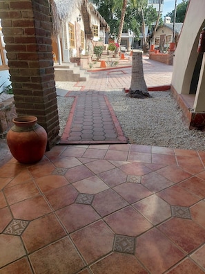 A courtyard with a tiled floor, a brick pillar, and a large terracotta pot. - Sandy Shores 7B (La Paz)