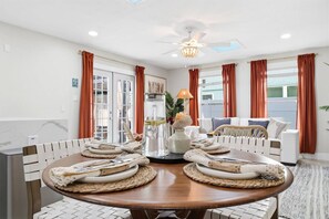 A dining area with a round table set for four, surrounded by white cushioned chairs. - Island Bliss - Update getaway steps from the beach, bars/restaurants & Kolb Park (Indian Rocks Beach)