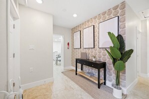 A hallway with a white door, a black console table with a plant, and a patterned wall. - Island Bliss - Update getaway steps from the beach, bars/restaurants & Kolb Park (Indian Rocks Beach)