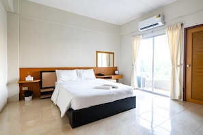 A hotel room with a bed, bedside tables, a mirror, an air conditioning unit, a window with curtains, and a door. - G room Suvarnablumi (Bangkok)