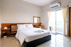 Habitació d'hotel amb llit, taula de nit, mirall, finestra amb cortines i aparell d'aire condicionat.
