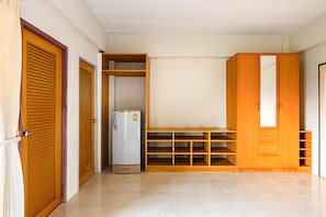 A room with a wardrobe, a built-in shelf unit, and a refrigerator. - G room Suvarnablumi (Bangkok)