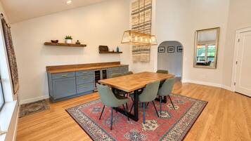 A modern kitchen with a wooden table and chairs, a ceiling fan, and a rug.