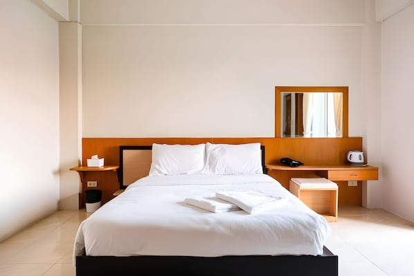 A hotel room with a bed, bedside tables, a nightstand, a mirror, and a small wooden cabinet. - S room Suvarnabhumi (Bangkok)