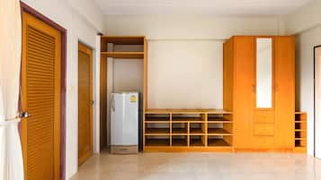 A room with a wardrobe, a built-in shelf unit, and a refrigerator.
