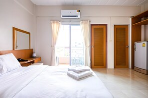 Habitació d'hotel amb llit, escriptori amb telèfon, aire condicionat i armari.