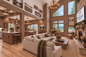 A spacious living room with a large sectional sofa, a fireplace, and a dining area with a view of the outdoors. - New Luxe Lakefront Lodge | Dock, Pool & Free Amenities | Min to Branson (Hollister)