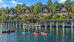 A lakeside property with multiple houses, a dock, and kayaks on the water. - Boat Lover's Escape! Lakefront Lodge + Slip, Pool, Pickleball, Golf (Hollister)