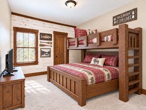A bunk bed with a wooden frame and plaid bedding, a desk with a computer, and a window with blinds. - Lakefront Lodge | River Views & Resort Fun | Pool, Golf & Dock (Hollister)