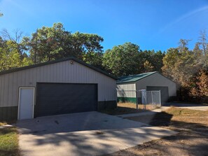 A two-story building with a garage and a fenced area. - Cozy 2-bedroom house in charming Danbury, WI on the Gandy Dancer Trail (Danbury)