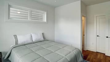 Bright minimalist bedroom with cozy bedding and warm wood floors