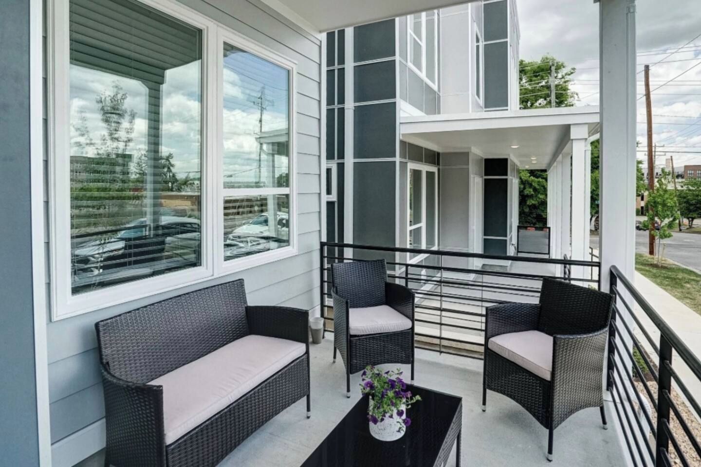 Un balcon agrémenté de meubles en osier et d’une plante en pot.