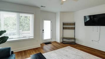 Bright living room with big windows, TV, and warm wood floors