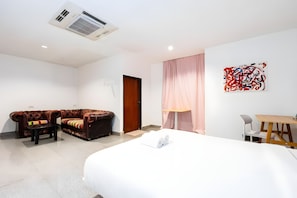 A modern hotel room with a bed, a sofa, a desk, and a painting on the wall. - M room Sukhumvit 2 (Bangkok)