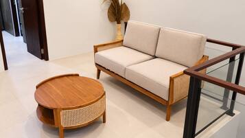 Una sala moderna con un sofá, una mesa de centro redonda de madera y un jarrón decorativo con plantas secas.