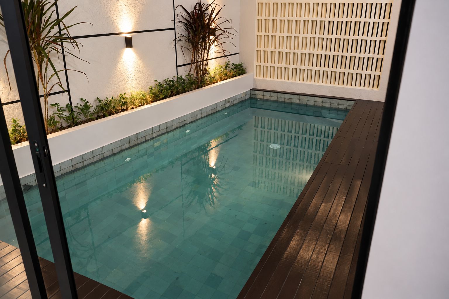 Una piscina interior con terraza de madera y paredes de cerámica.