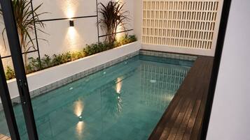 Una piscina interior con terraza de madera y paredes de cerámica.